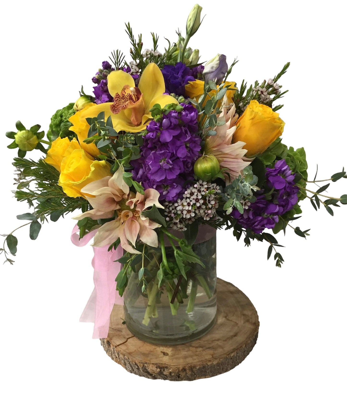 Bouquet of yellow and purple flowers in a glass vase on a wooden coaster with a white background