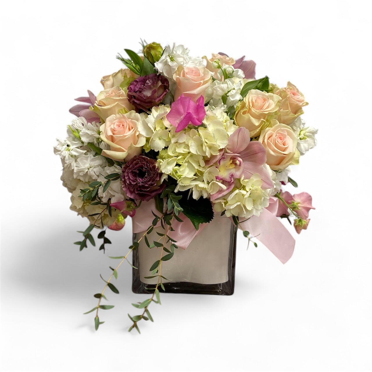 Bouquet of flowers with pink and white roses in a clear vase on a white background