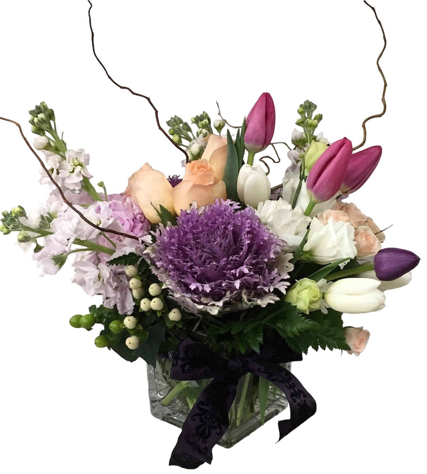 Bouquet of flowers with purple, white, and green colors in a clear vase on a white background