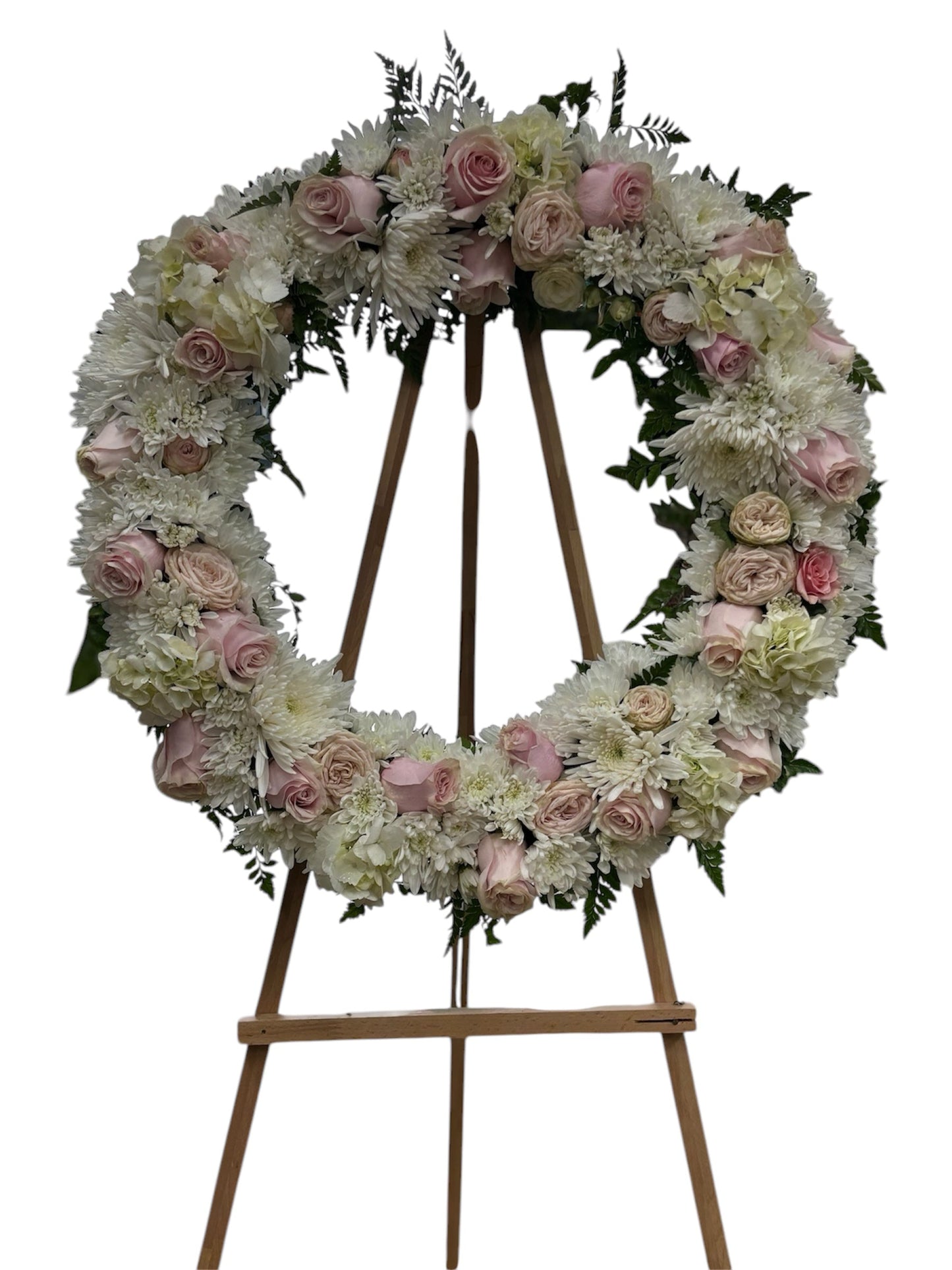 Floral wreath with pink and white flowers on a wooden easel against a white background
