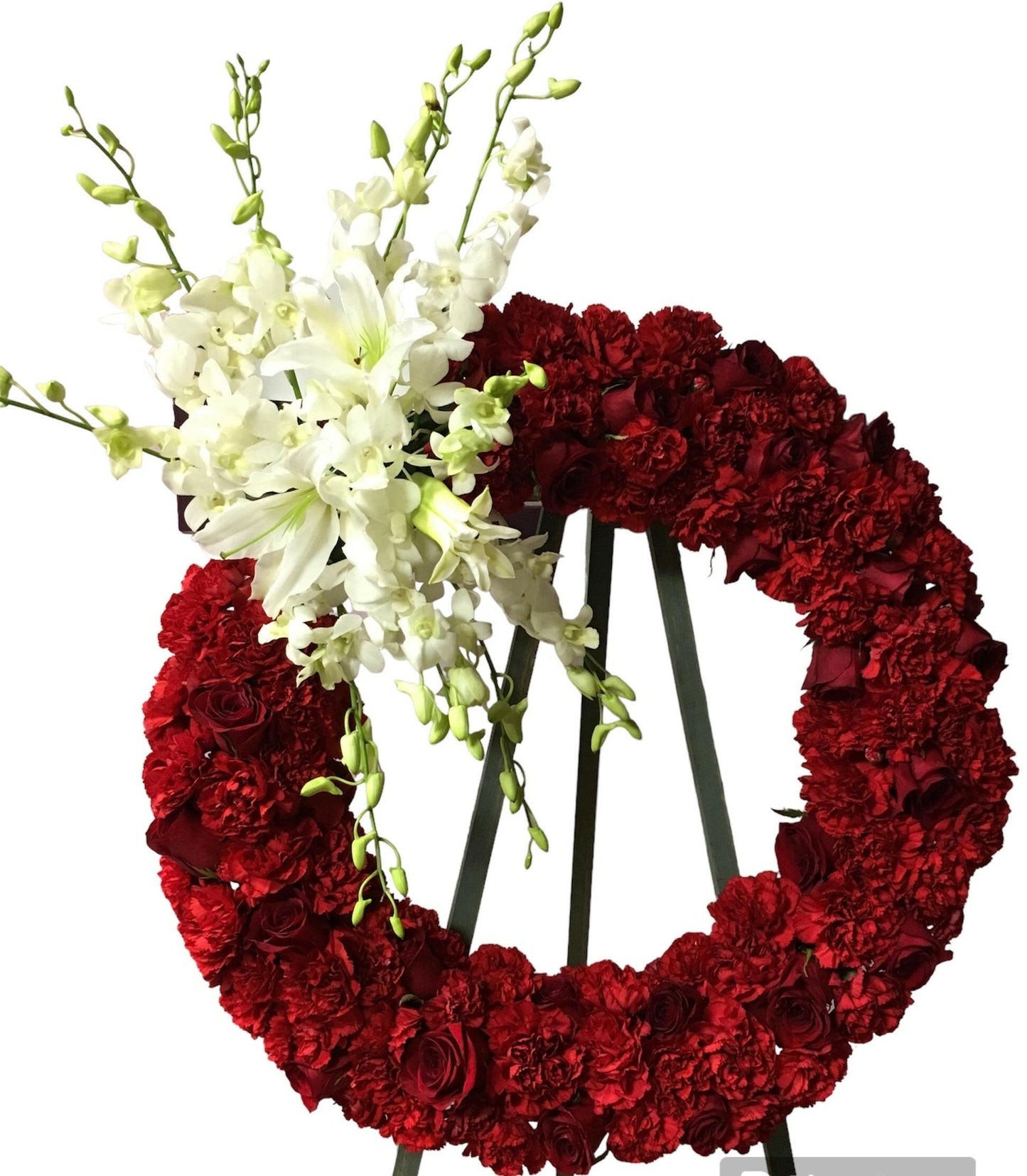 Red floral wreath with white flowers on a stand against a white background