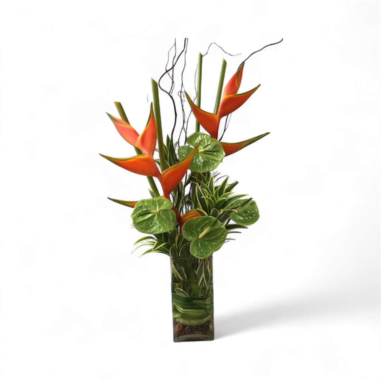 Artificial tropical plant arrangement in a clear glass vase on a white background