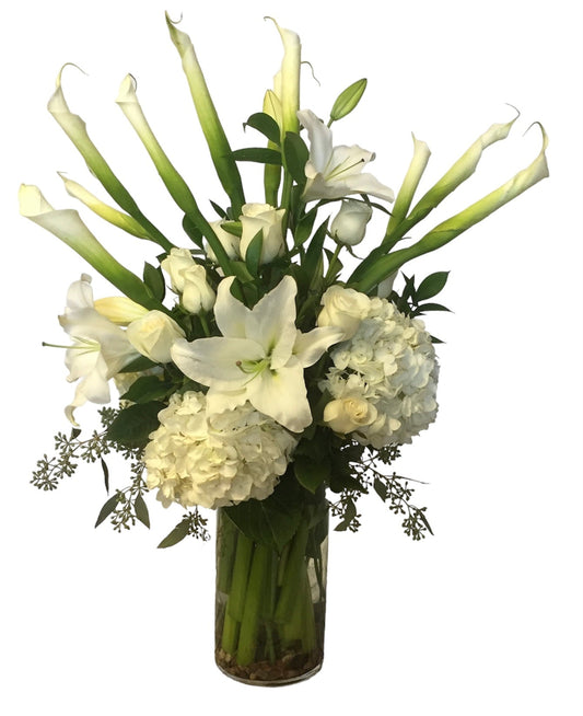 Bouquet of white lilies and hydrangeas in a clear vase on a white background