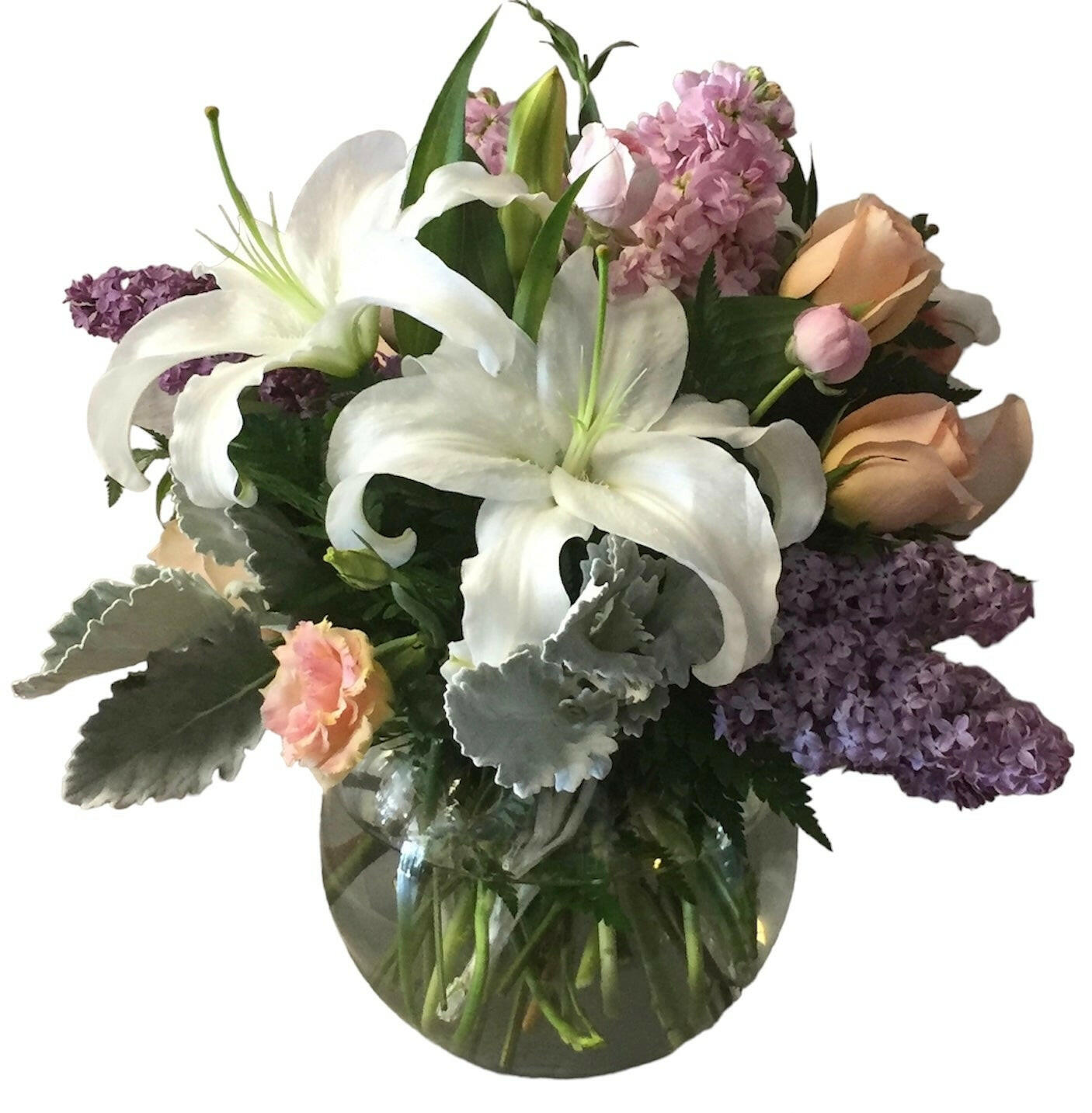Bouquet of flowers with white lilies, pink roses, and purple hydrangeas in a clear vase on a white background.