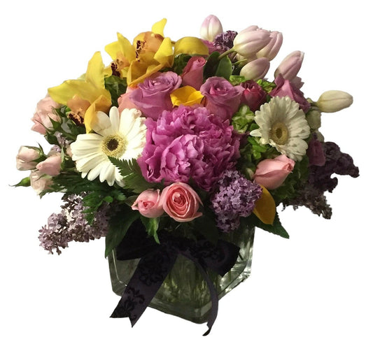 Bouquet of colorful flowers with a black ribbon in a clear vase on a white background
