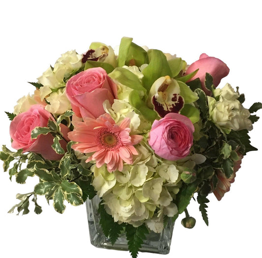 Bouquet of pink and green flowers in a clear vase on a white background