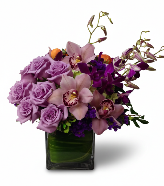 Bouquet of purple roses and orchids in a clear vase 