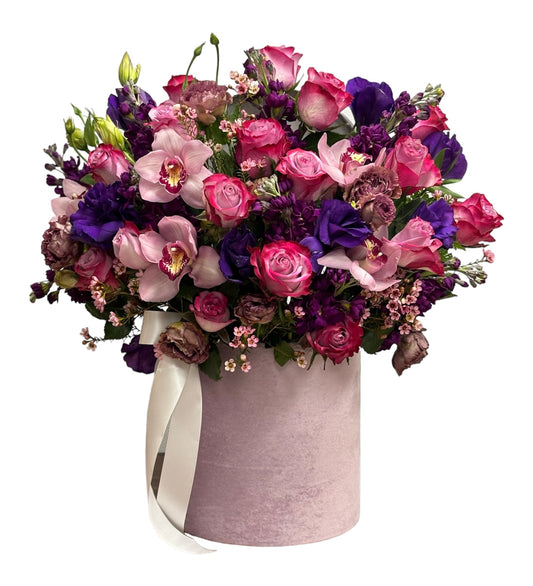 Bouquet of pink and purple flowers in a oink valvet container on a white background