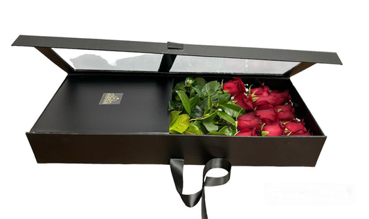 Black gift box with red roses and green leaves on a white background