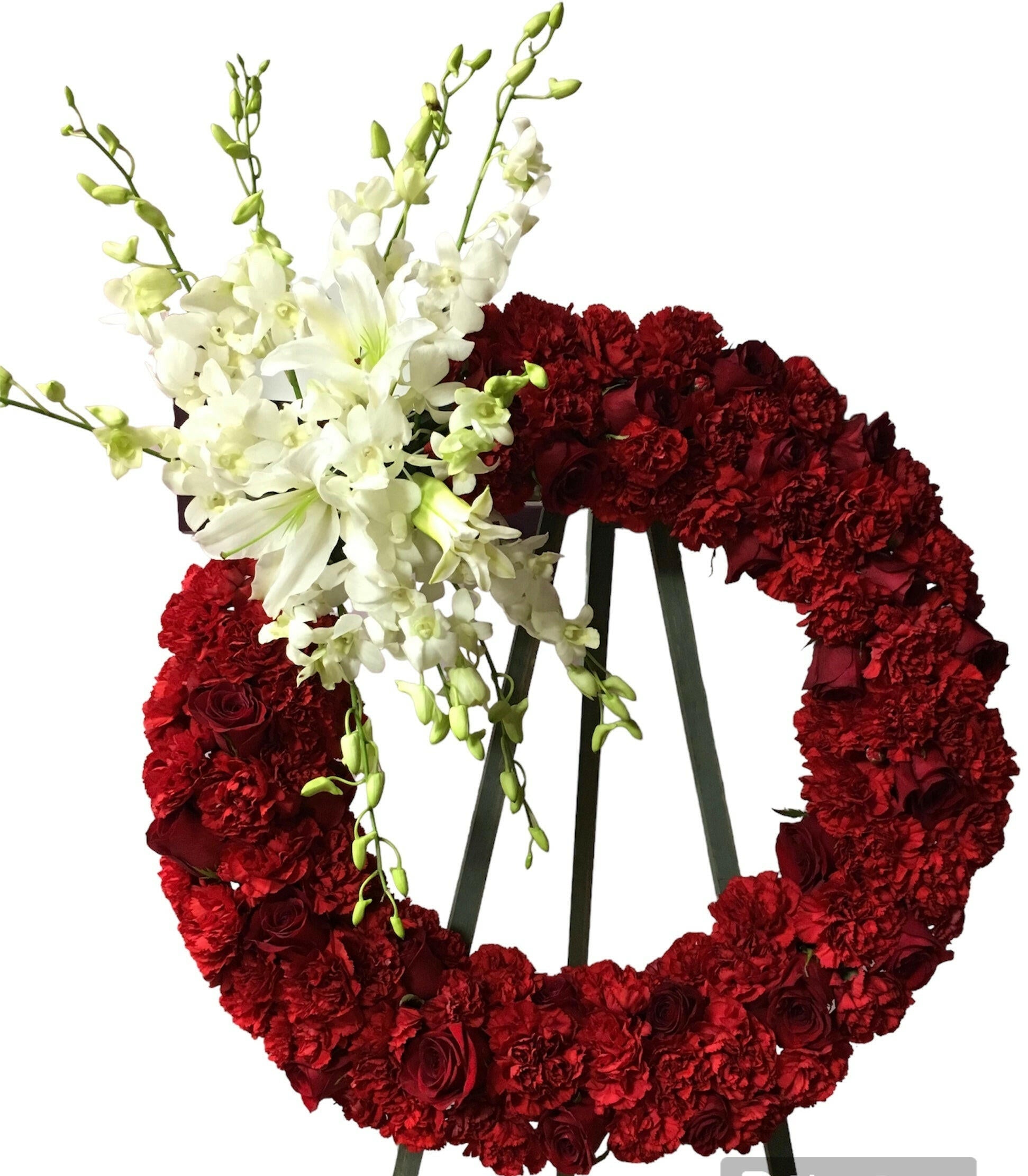 Red floral wreath with white flowers on a stand against a white background