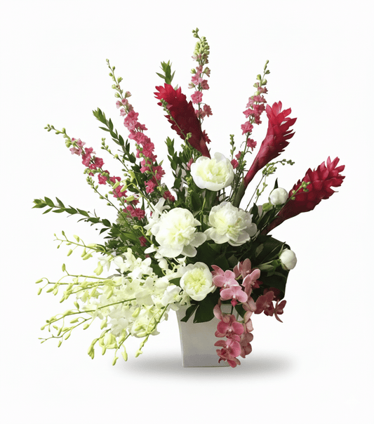 A tall, elegant floral arrangement in a white vase, featuring white peonies, red ginger, red and pink snapdragons, and white and pink orchids.