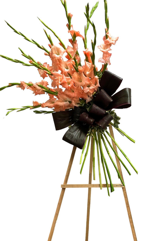Floral arrangement with pink flowers and a black bow on a white background