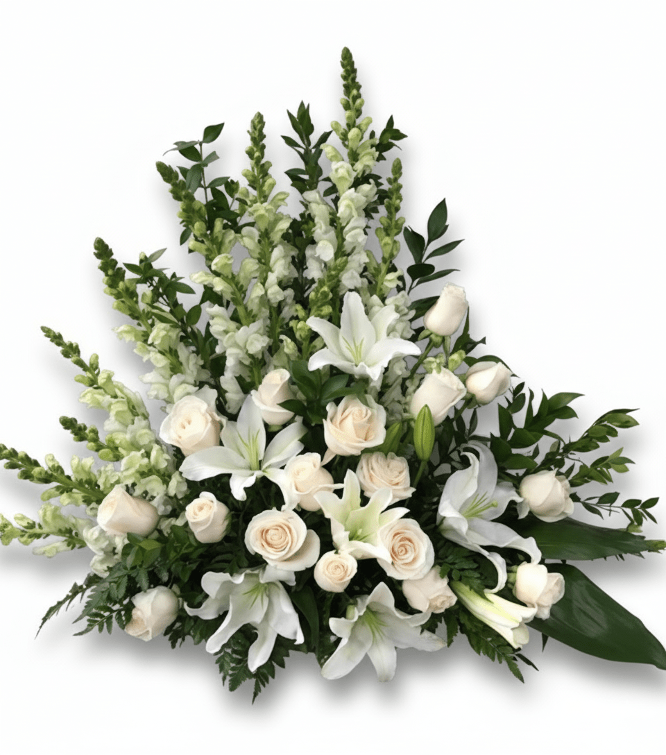 Large white and cream floral sympathy or memorial arrangement with lilies, roses, and snapdragons, isolated on white.