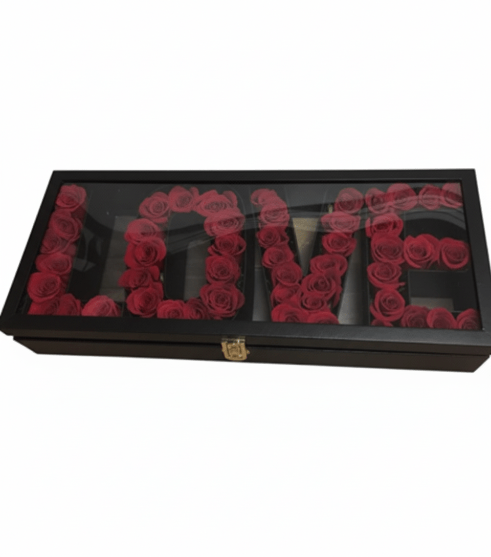 A black rectangular box with a clear lid, containing deep red roses meticulously arranged in separate compartments to spell out the word 'L-O-V-E', with a gold clasp on the front, against a white background.