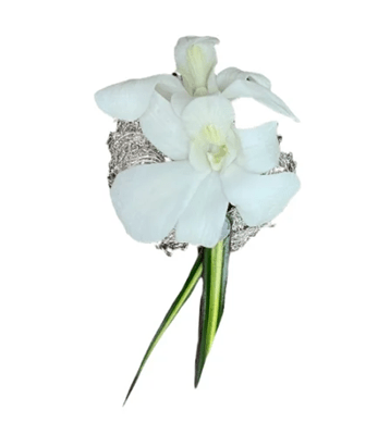 A boutonniere featuring a single white orchid, a small cluster of tiny white filler flowers, a silvery textured wire accent, and a pointed green and yellow leaf, against a white background.