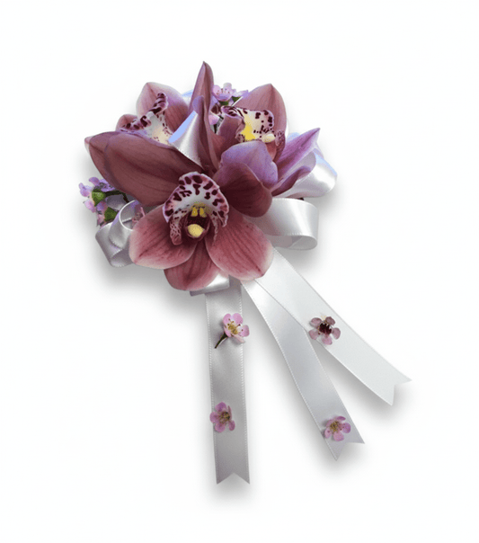 Pink orchid corsage with white ribbons on a white background