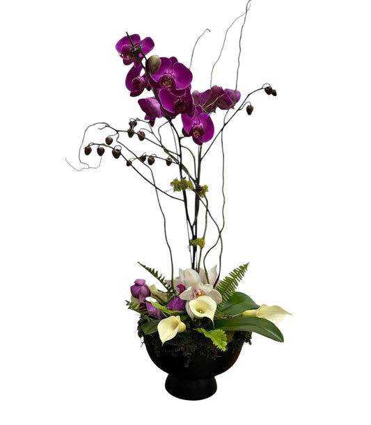 Floral arrangement with purple orchids and white calla lilies in a black container on a white background