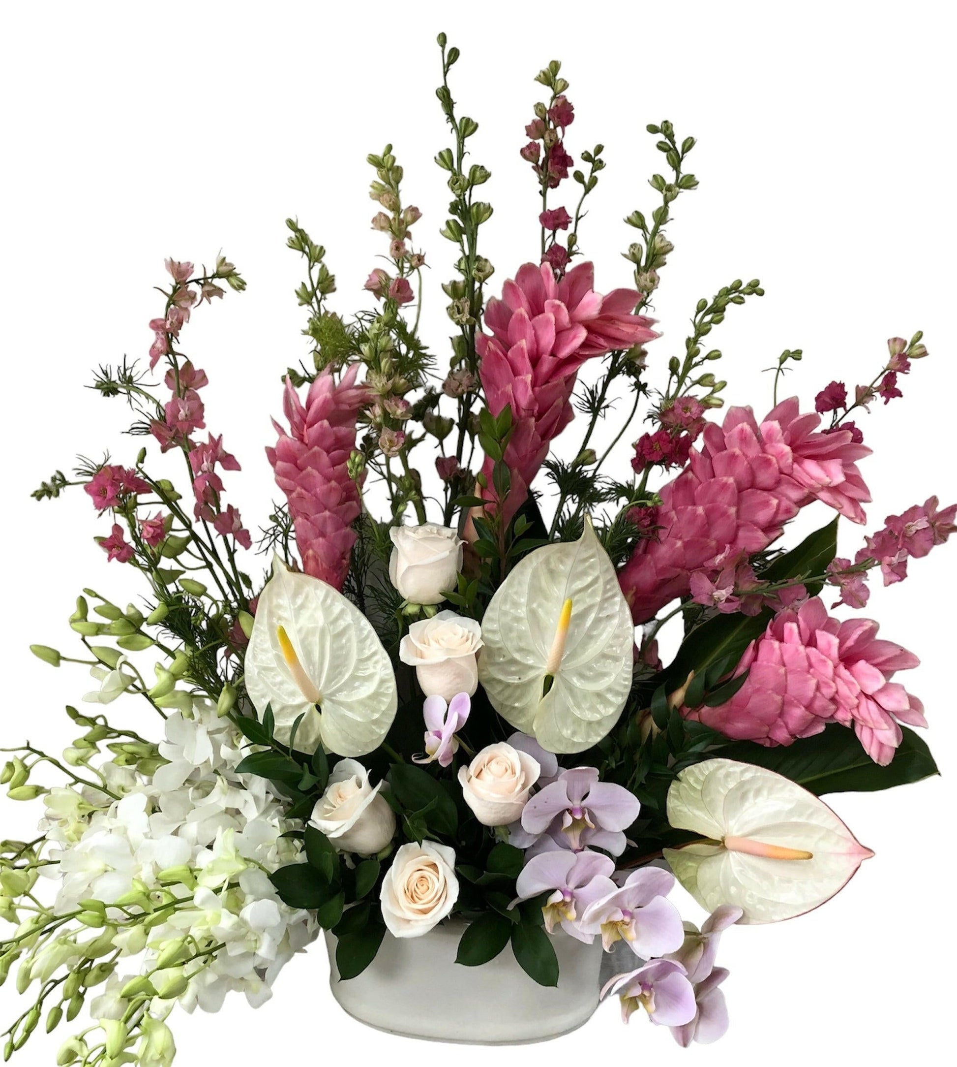 Colorful tropical flower arrangement with pink, white, and green flowers in a white vase on a white background