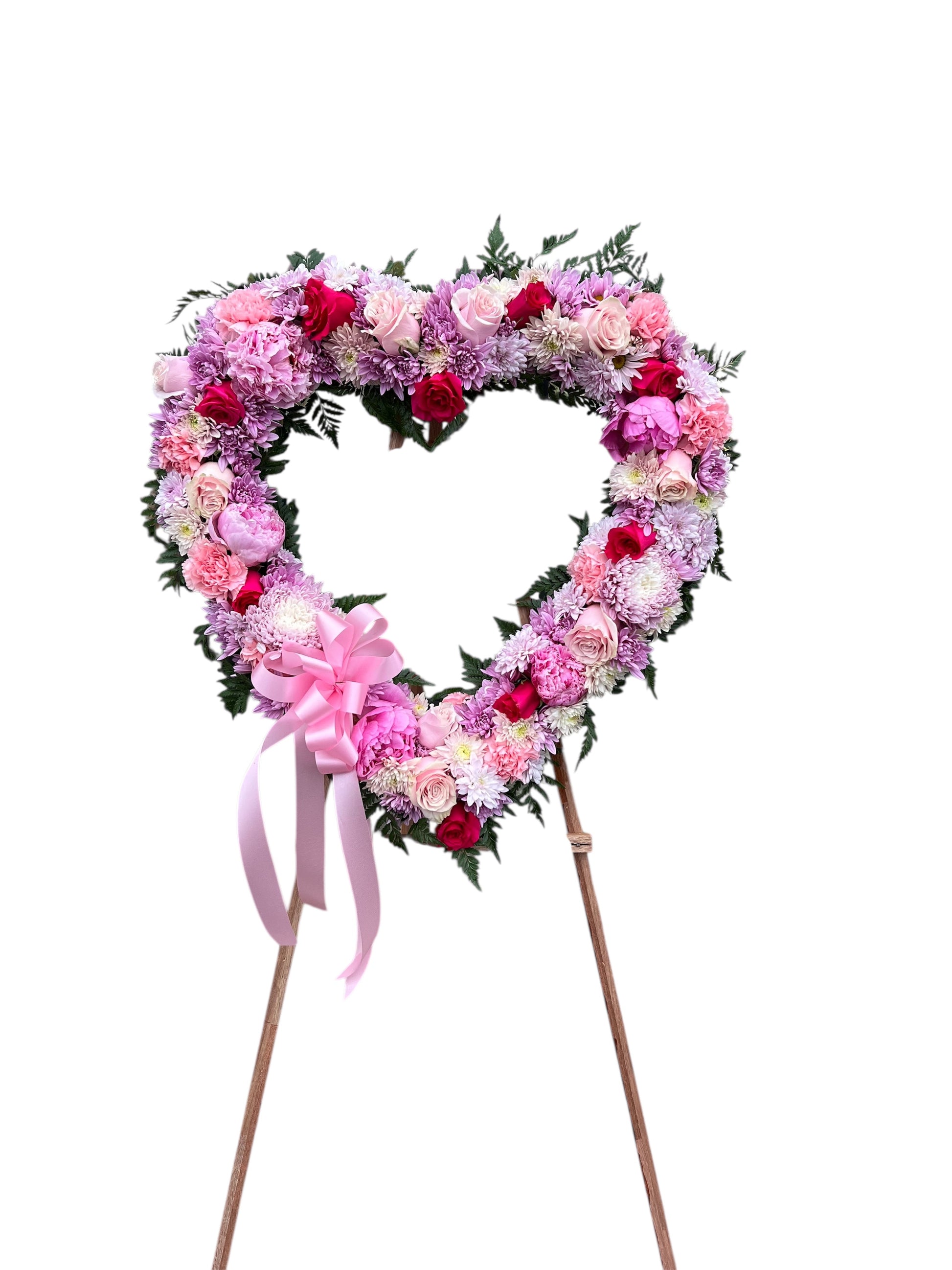 Heart-shaped floral arrangement with pink and white flowers on a stand against a white background